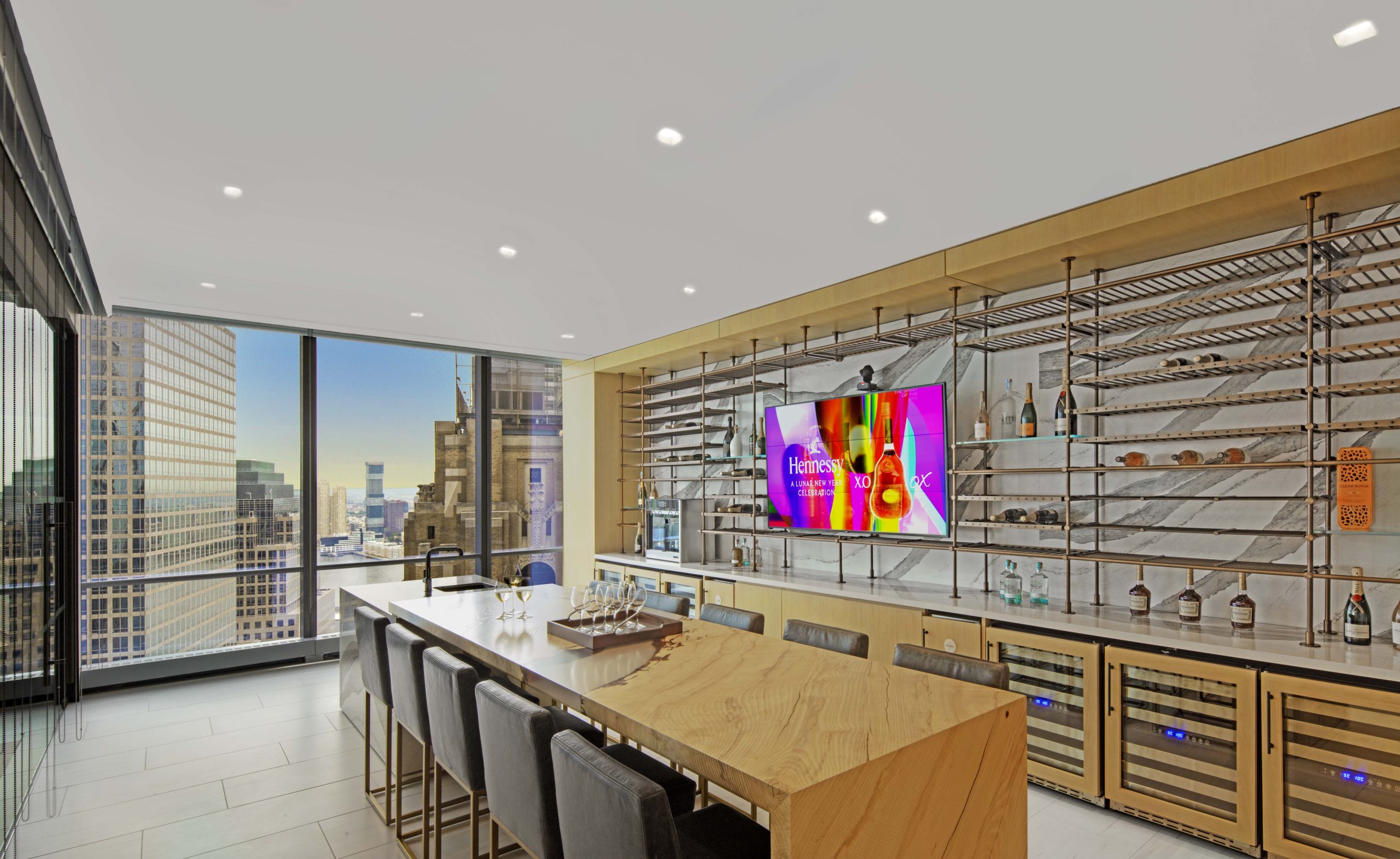 Bronze Wine display surrounding TV in corporate kitchen island bar area overlooking manhattan skyline